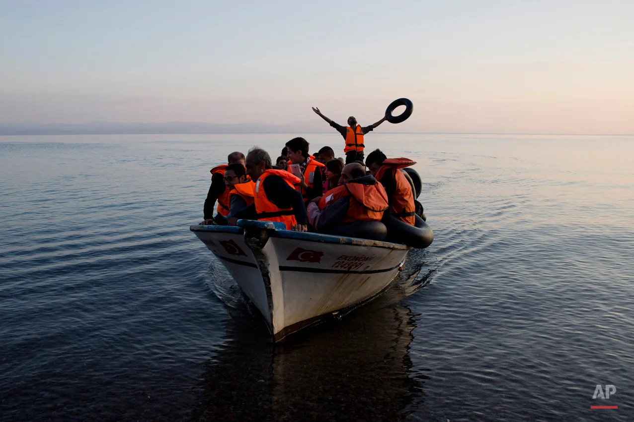 A Syrian refugee praises god as he arrive with others from Turkey on the shores of the Greek island of Lesbos, on a fishing boat, Sunday Sept. 27, 2015. More than 260,000 asylum-seekers have arrived in Greece so far this year, most reaching the country's eastern islands on flimsy rafts or boats from the nearby Turkish coast.(AP Photo/Petros Giannakouris)