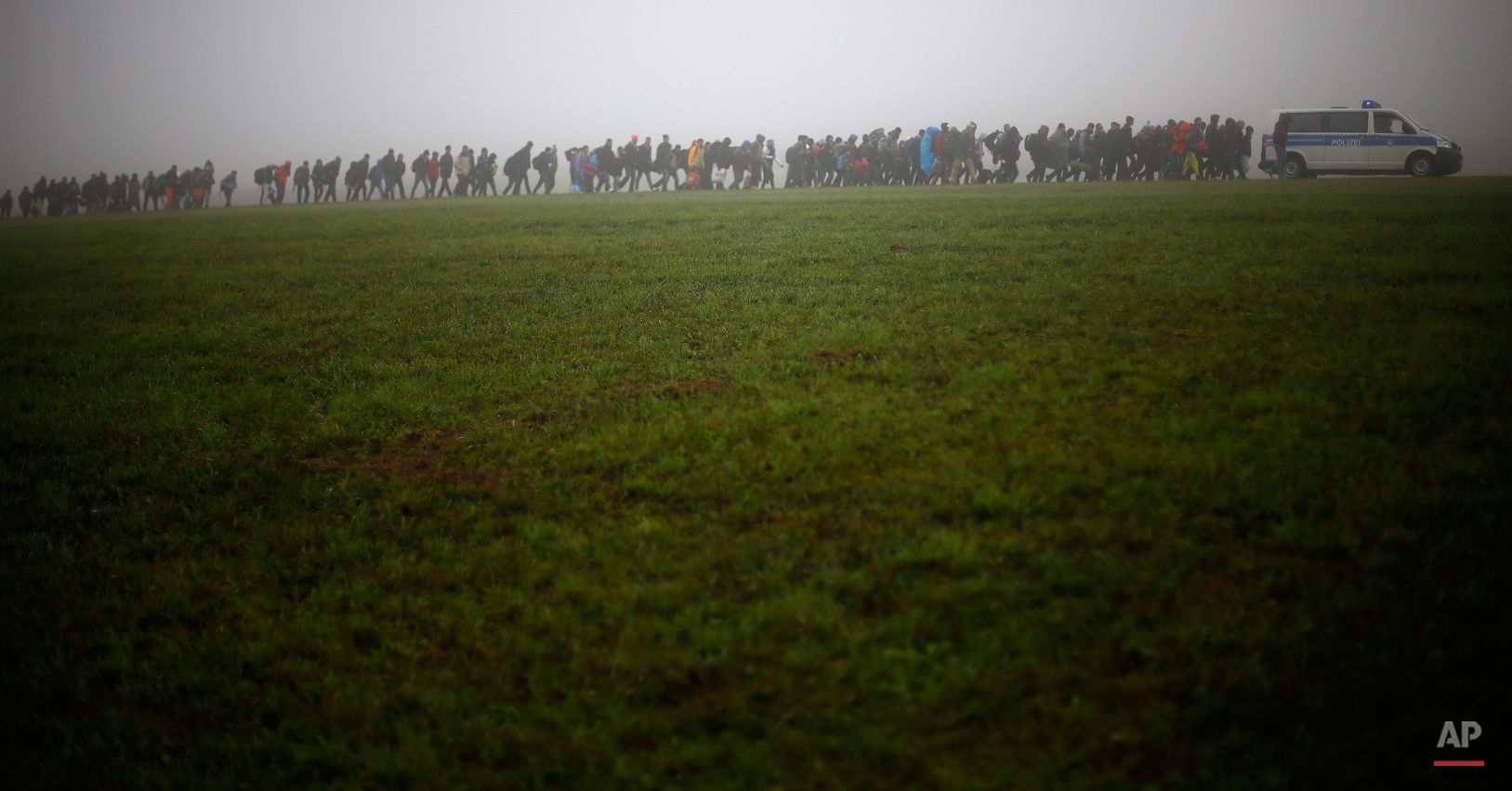  German federal police officers guide a group of migrants on their way after crossing the border between Austria and Germany in Wegscheid near Passau, Germany, Thursday, Oct. 15, 2015. (AP Photo/Matthias Schrader) 