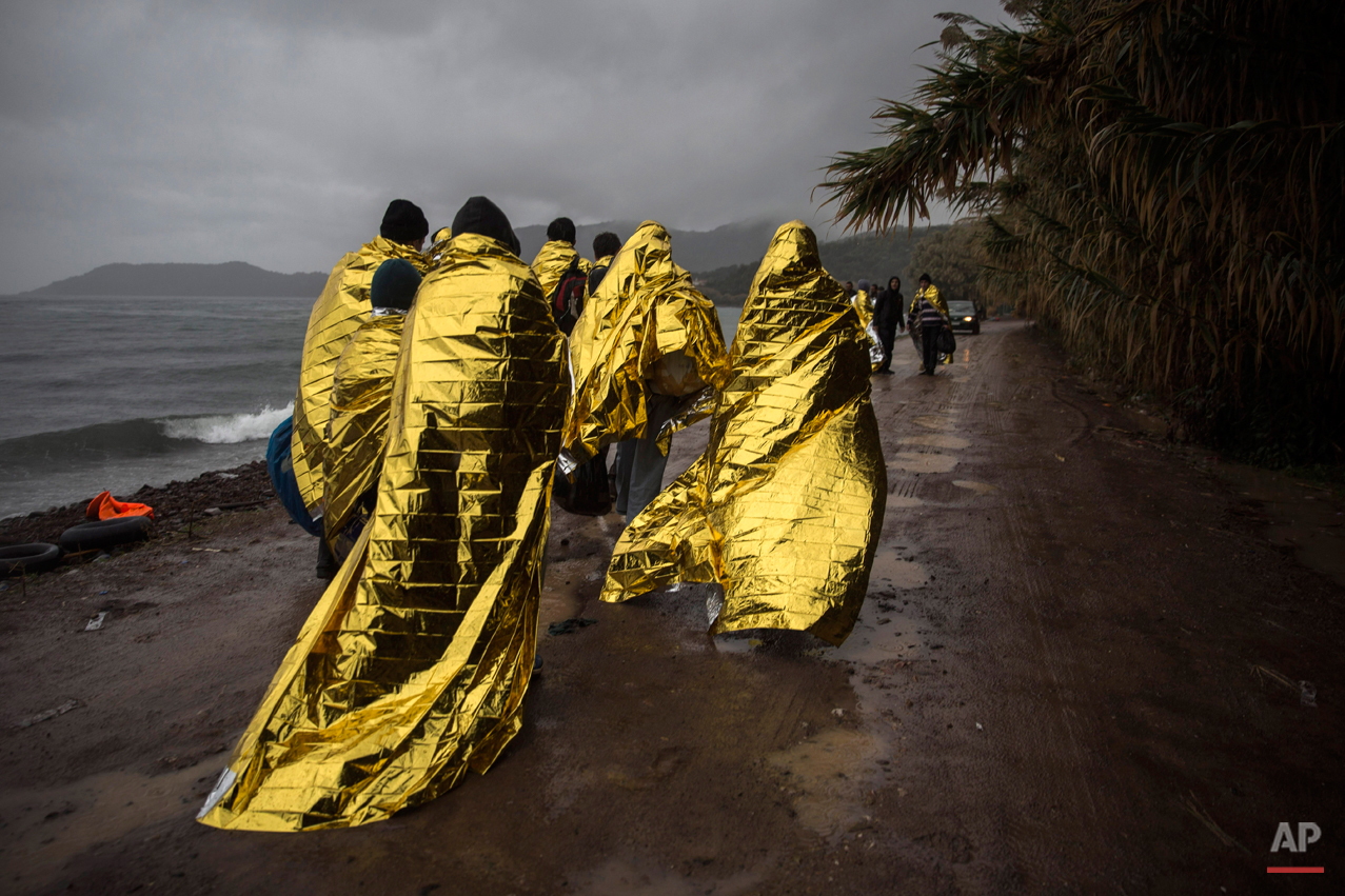  Refugees and migrants are covered with thermal blankets after their arrival on a dinghy from the Turkish coast to the Skala Sykaminias village on the northeastern Greek island of Lesbos, Friday, Oct. 23, 2015. The International Office for Migration 
