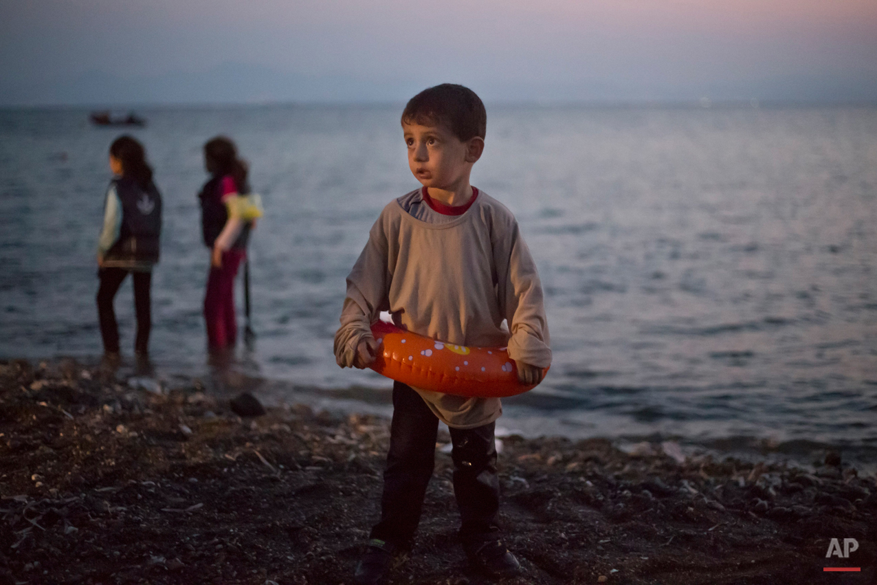  A Syrian migrant boy still wearing a swimming ring stands on the beach upon his arrival with other migrants by a dinghy at the southeastern Greek island of Kos, Greece, early Thursday, Aug. 20, 2015. (AP Photo/Alexander Zemlianichenko) 