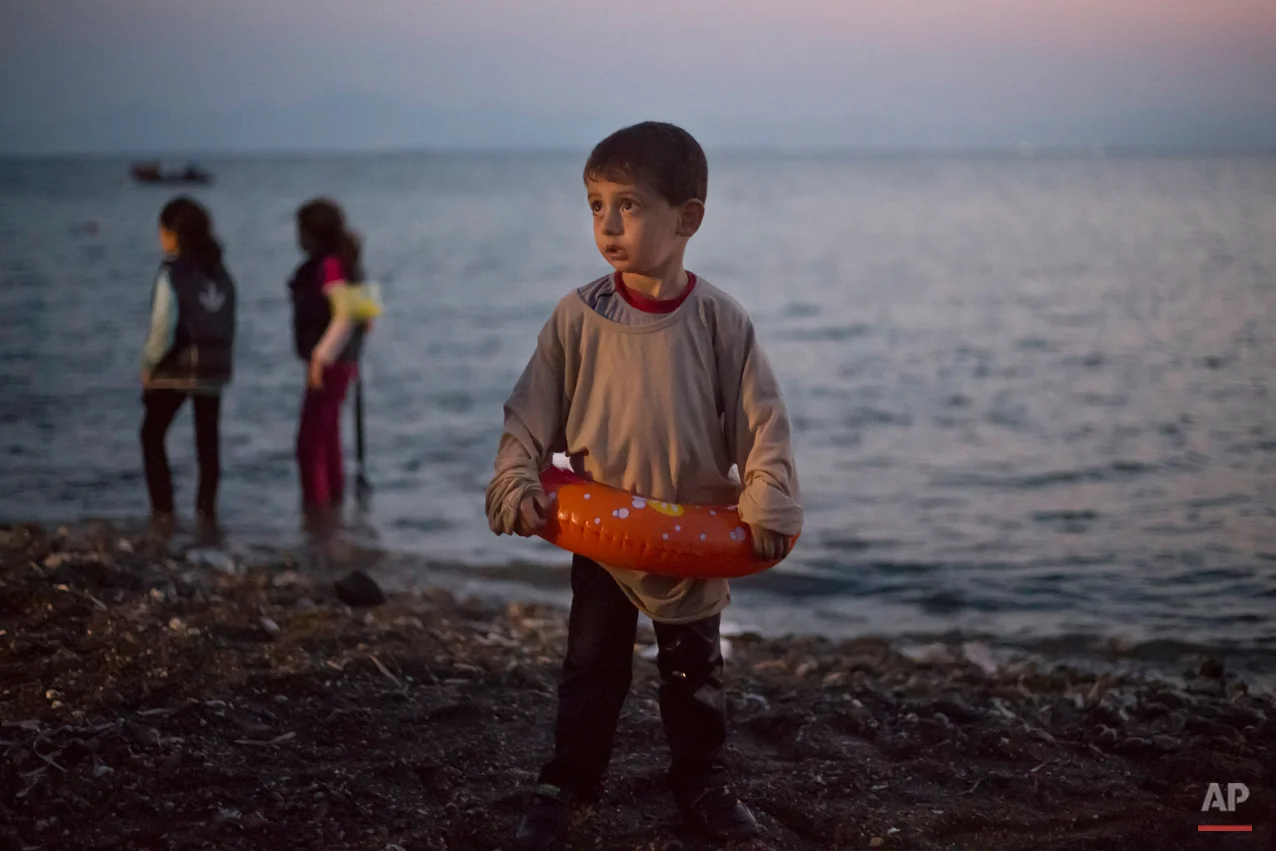 A Syrian migrant boy still wearing a swimming ring stands on the beach upon his arrival with other migrants by a dinghy at the southeastern Greek island of Kos, Greece, early Thursday, Aug. 20, 2015. (AP Photo/Alexander Zemlianichenko)