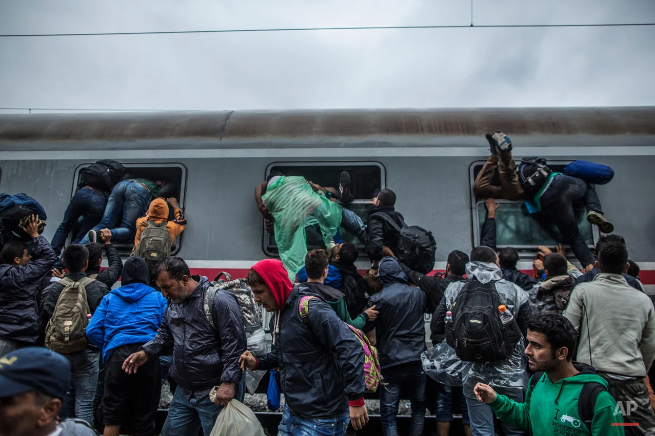 Migrants and refugees board a train by climbing through the windows as they try to avoid a police barrier at the station in Tovarnik, Croatia, Sunday, Sept. 20, 2015. (AP Photo/Manu Brabo)