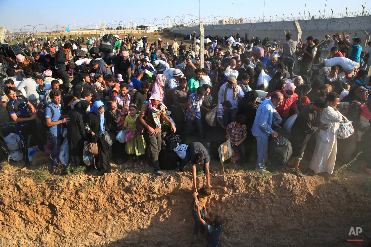  Syrian refugees walk into Turkey after breaking the border fence and crossing from Syria in Akcakale, Sanliurfa province, southeastern Turkey, Sunday, June 14, 2015. The mass displacement of Syrians across the border into Turkey comes as Kurdish fig