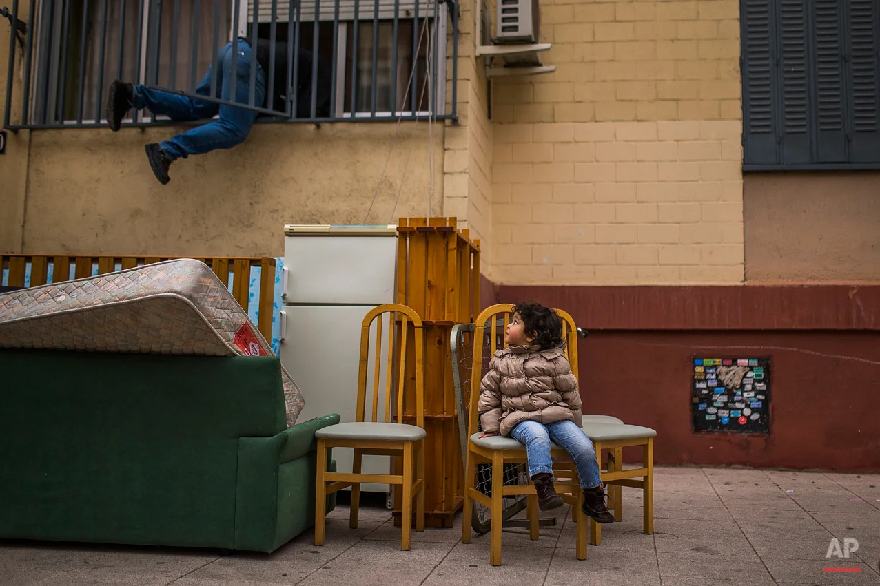 In this Wednesday, Feb. 11, 2015, photo, Diana Sofia Meliton, 2 years old, sits outside together with belongings after her and her family got evicted by the police and watches a housing right activist re-opening her apartment for them to live in Madrid, Spain. (AP Photo/Andres Kudacki)