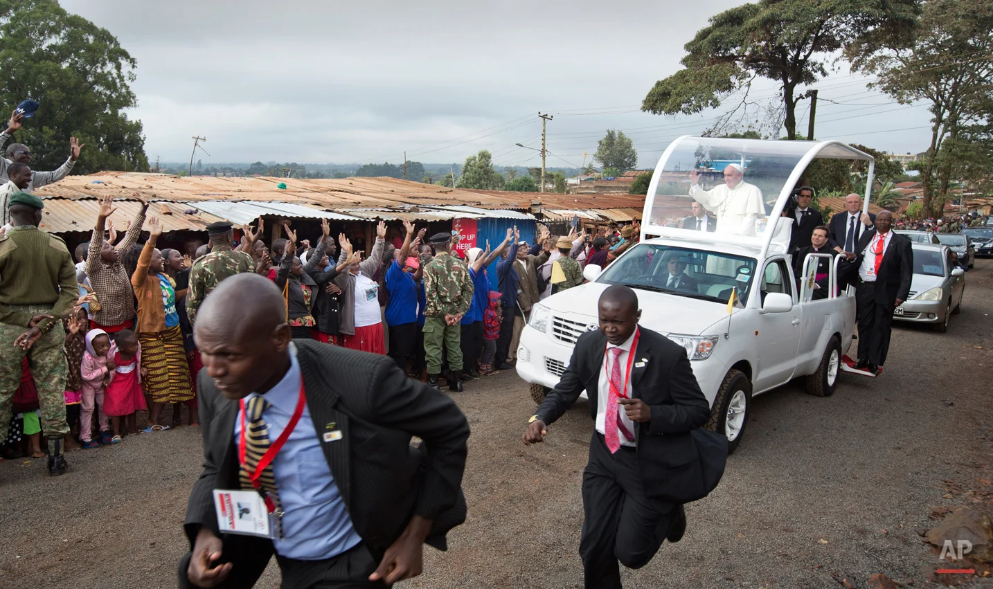 Pope Francis waves to local residents as he drives to St. Joseph The Worker Catholic Church in the Kangemi slum of Nairobi, Kenya Friday, Nov. 27, 2015. Pope Francis is in Kenya on his first-ever trip to Africa, a six-day pilgrimage that will also take him to Uganda and the Central African Republic. (AP Photo/Ben Curtis)