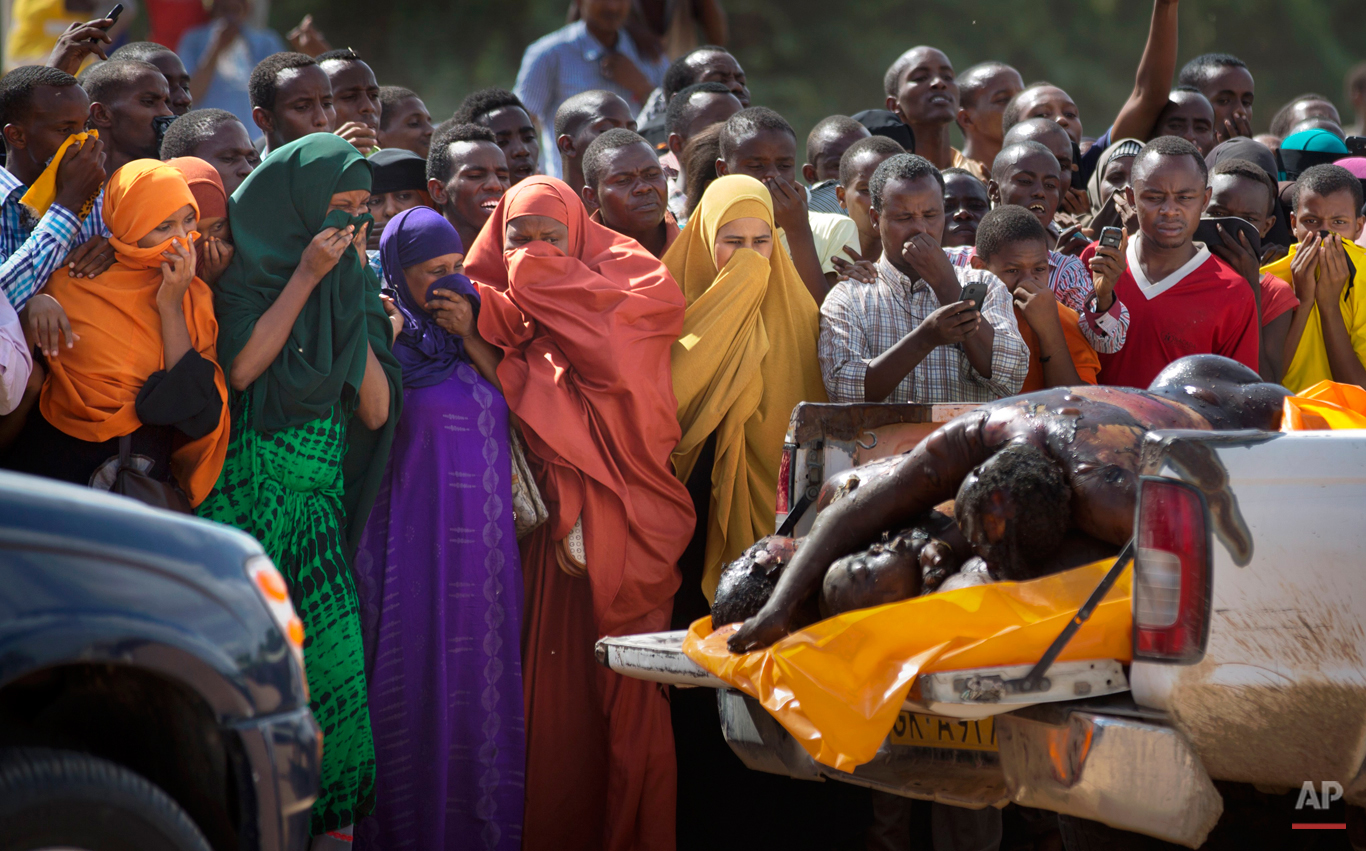  Women in the crowd cover their faces to protect against the smell as authorities display the bodies of the alleged attackers before about 2,000 people in a large open area in central Garissa, Kenya Saturday, April 4, 2015. (AP Photo/Ben Curtis) 