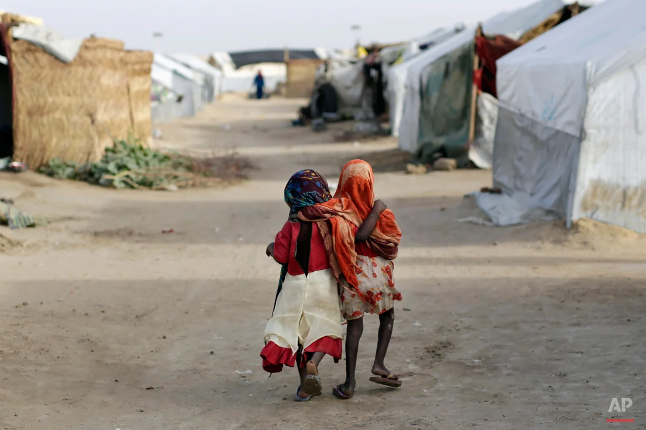 Ami and Ashbu, both three-years-old, walk arm in arm in the Zafaye refugee camp, some 15 kms (10 miles) from downtown N'djamena, Chad, Wednesday March 11, 2015. Both from the PK5 district of Bangui, have been living in the camp for over a year with over 5000 other refugees of Chadian descent who fled the fighting in Central African Republic. Chad is also hosting thousands of refugees fleeing the current Boko Haram fighting in Nigeria. (AP Photo/Jerome Delay)