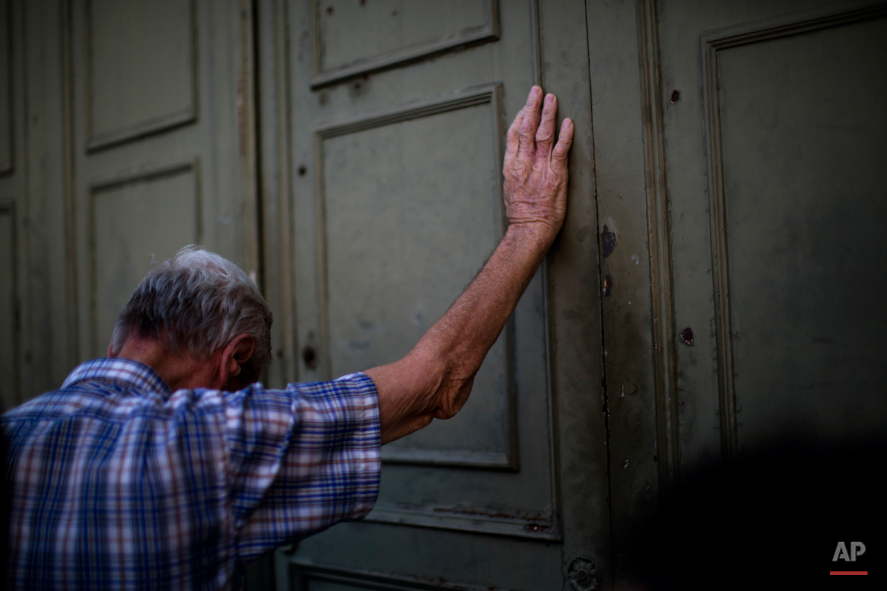  A pensioner leans against the main gate of the national bank of Greece as he waits to withdraw a maximum of 120 euros ($134) for the week in Athens in central Athens, Tuesday, July 7, 2015. (AP Photo/Emilio Morenatti) 