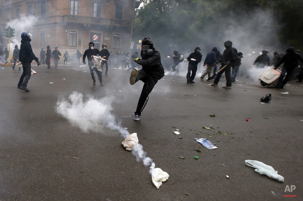A demonstrators kicks a teargas canister as clashes broke out with Italian Policemen during a protest against the Expo 2015 fair in Milan, Italy, Friday, May 1, 2015. (AP Photo/Luca Bruno)