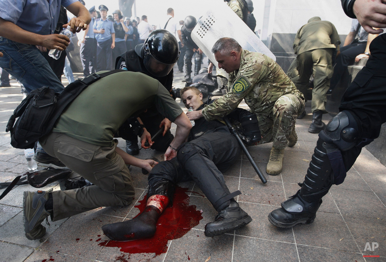 Police officers give a person medical aid after a grenade blast during clashes between protesters and police following a vote to give greater powers to the east, outside the Parliament in Kiev, Ukraine, Monday, Aug. 31, 2015. The Ukrainian parliament has given preliminary approval to a controversial constitutional amendment that would provide greater powers to separatist regions in the east. Hundreds of people gathered in front of the parliament to protest the amendment. (AP Photo/Vladimir Donsov)