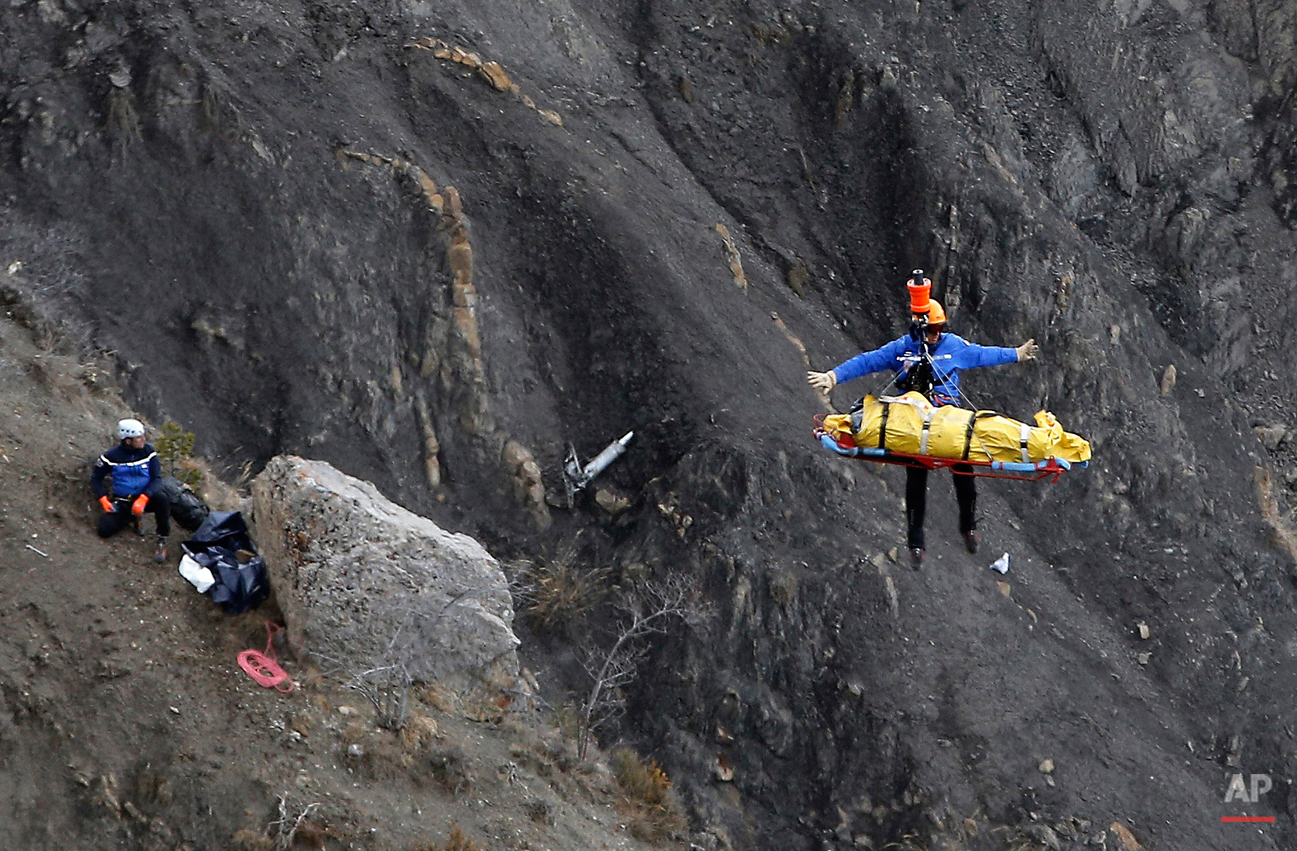  A rescue worker is lifted into an helicopter at the crash site near Seyne-les-Alpes, France, Thursday, March 26, 2015. The co-pilot of a Germanwings jet barricaded himself in the cockpit and rammed the plane full speed into the French Alps, ignoring