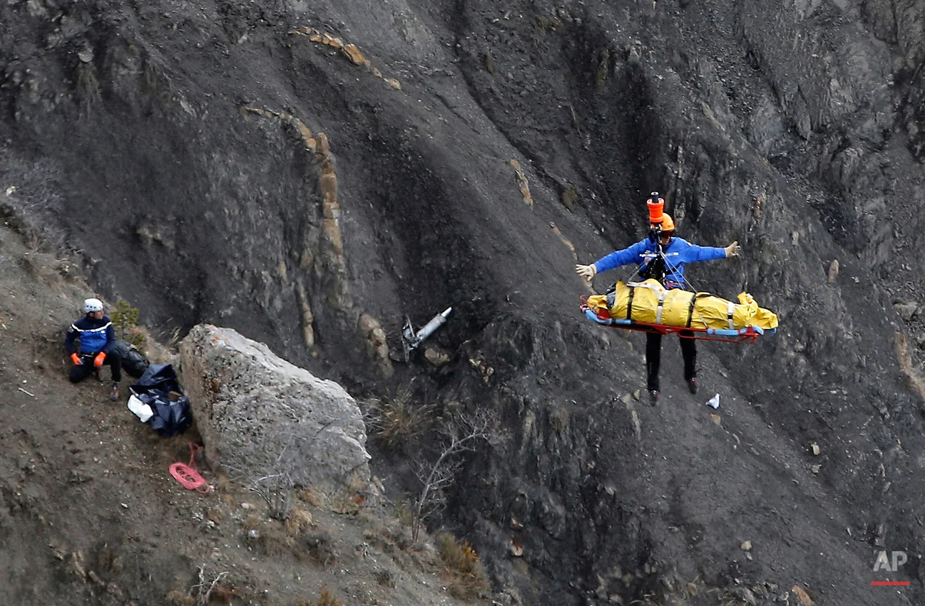 A rescue worker is lifted into an helicopter at the crash site near Seyne-les-Alpes, France, Thursday, March 26, 2015. The co-pilot of a Germanwings jet barricaded himself in the cockpit and rammed the plane full speed into the French Alps, ignoring the captain's frantic pounding on the cockpit door and the screams of terror from passengers. In a split second, he killed all 150 people aboard the plane. (AP Photo/Laurent Cipriani)