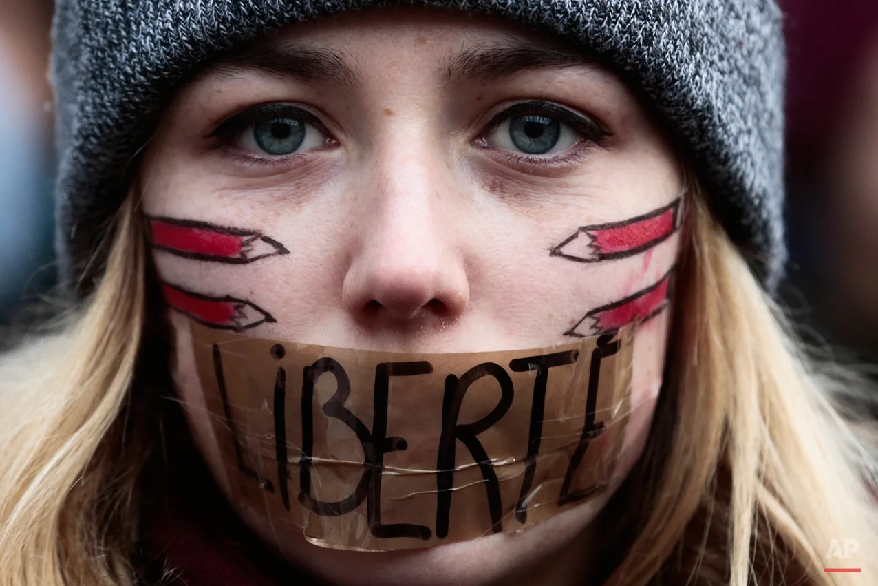 A woman has taped her mouth displaying the word Freedom on the tape as she gathers with several thousand people in solidarity with victims of two terrorist attacks in Paris, one at the office of weekly newspaper Charlie Hebdo and another at a kosher market, in front of the Brandenburg Gate near the French embassy in Berlin, Sunday, Jan. 11, 2015. (AP Photo/Markus Schreiber)