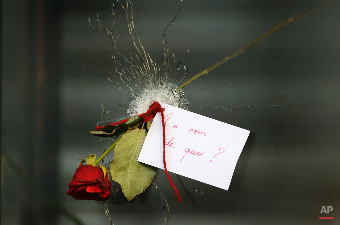  A message that reads: "In the name of what?" and a rose is placed through a bullet hole in a window at the restaurant on Rue de Charonne, Paris, Sunday, Nov. 15, 2015, where attacks took place on Friday. The Islamic State group claimed responsibilit