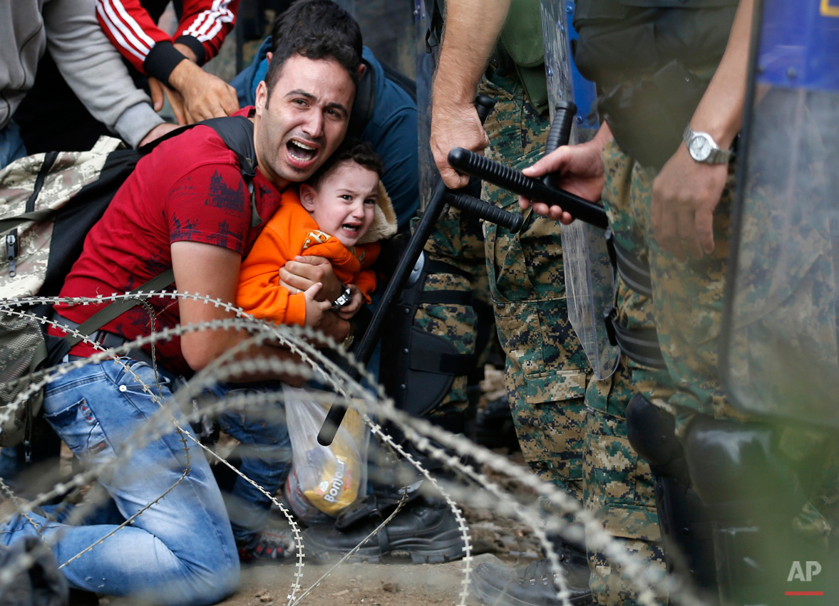  Macedonian riot police officers clash with migrants near the border train station of Idomeni, northern Greece, as they wait to be allowed by the Macedonian police to cross the border from Greece to Macedonia, Friday, Aug. 21, 2015. Macedonian specia