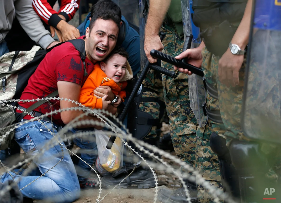 Macedonian riot police officers clash with migrants near the border train station of Idomeni, northern Greece, as they wait to be allowed by the Macedonian police to cross the border from Greece to Macedonia, Friday, Aug. 21, 2015. Macedonian special police forces have fired stun grenades to disperse thousands of migrants stuck on a no-man's land with Greece, a day after Macedonia declared a state of emergency on its borders to deal with a massive influx of migrants heading north to Europe. (AP Photo/Darko Vojinovic)