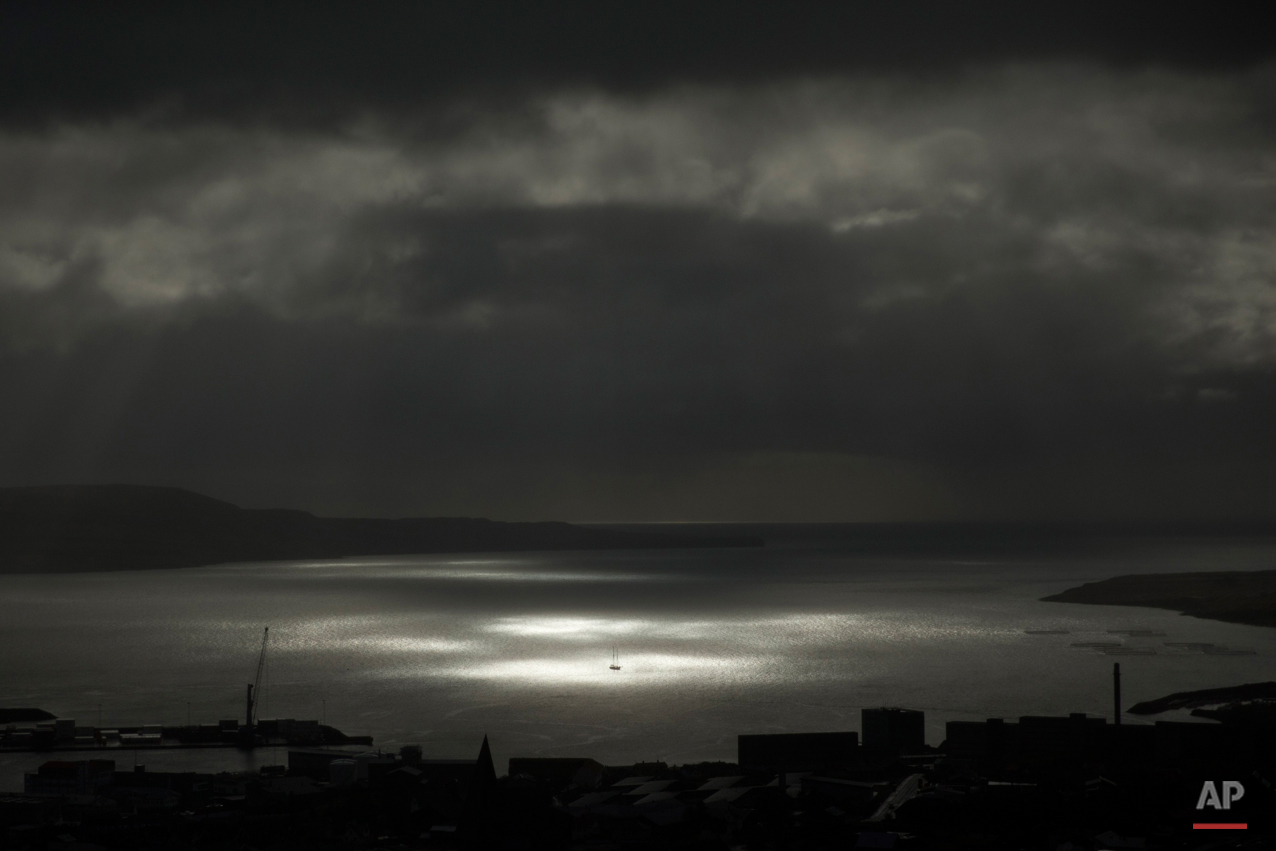  A spot of sunlight breaks through the clouds and shines on a vessel on the sea during the partial phase of a solar eclipse before totality as seen from a hill beside a hotel on the edge of the city overlooking Torshavn, the capital of the Faeroe Isl