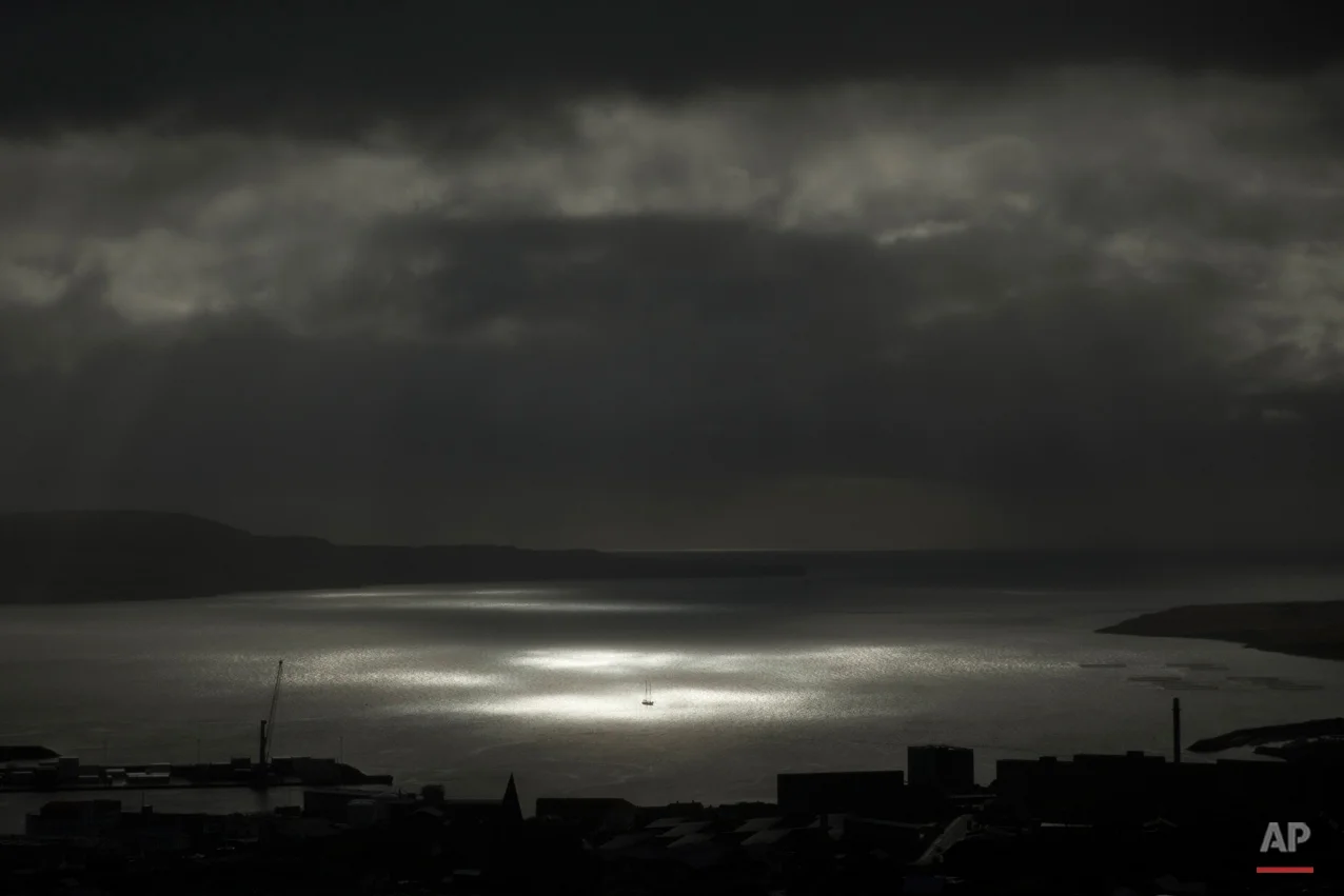 A spot of sunlight breaks through the clouds and shines on a vessel on the sea during the partial phase of a solar eclipse before totality as seen from a hill beside a hotel on the edge of the city overlooking Torshavn, the capital of the Faeroe Islands, Friday, March 20, 2015. A blanket of clouds in the Faeroe Islands blocked thousands of people there from experiencing the full effect of the total eclipse. The clouds then cleared after totality. (AP Photo/Matt Dunham)