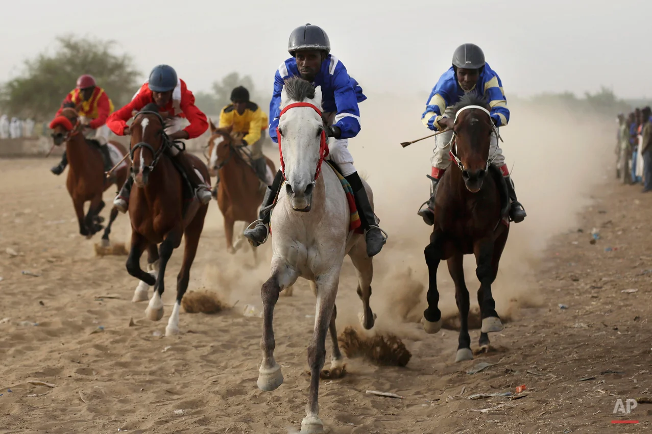 In this Sunday, March 15, 2015 photo, Chadian jockeys race to the finish line during an afternoon of races at the hippodrome in N'djamena, Chad. Horse races take place every Sunday, bringing hundreds of spectators willing to brave the excruciating heat to watch their favorite sport.(AP Photo/Jerome Delay)