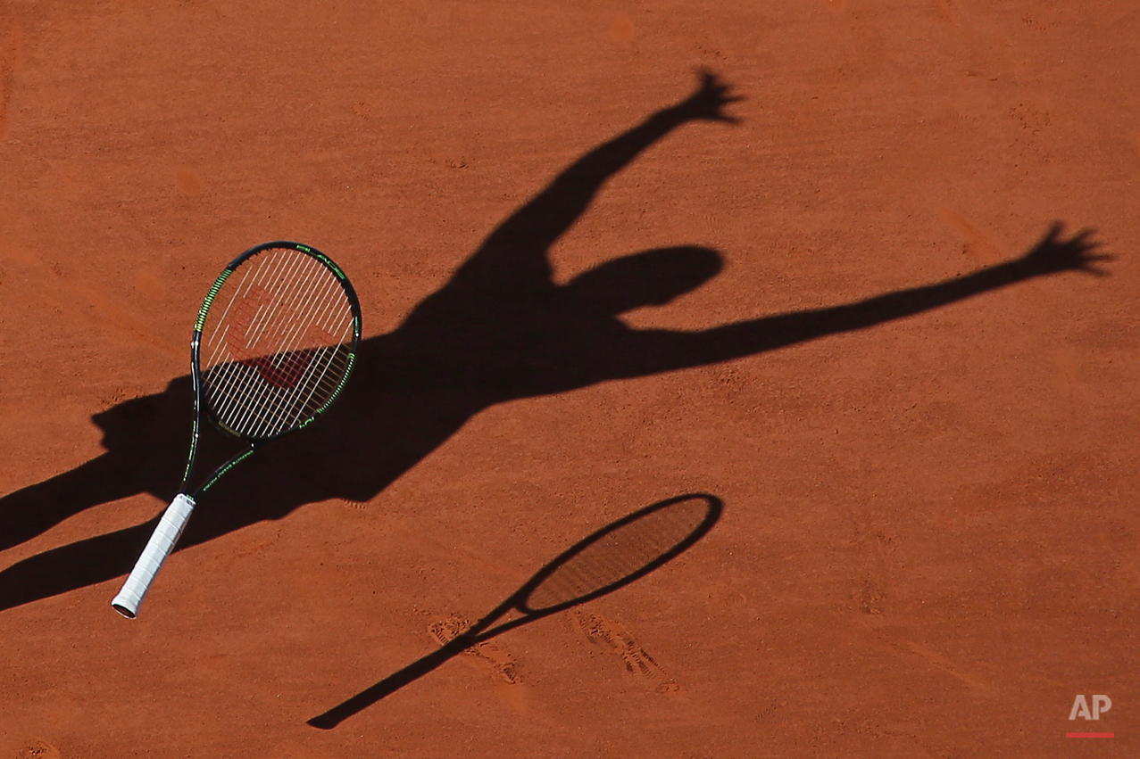  In this Saturday June 6, 2015 photo, Serena Williams of the U.S. casts a shadow on the clay as she drops her racket and celebrates winning the final of the French Open tennis tournament against Lucie Safarova of the Czech Republic in three sets, 6-3