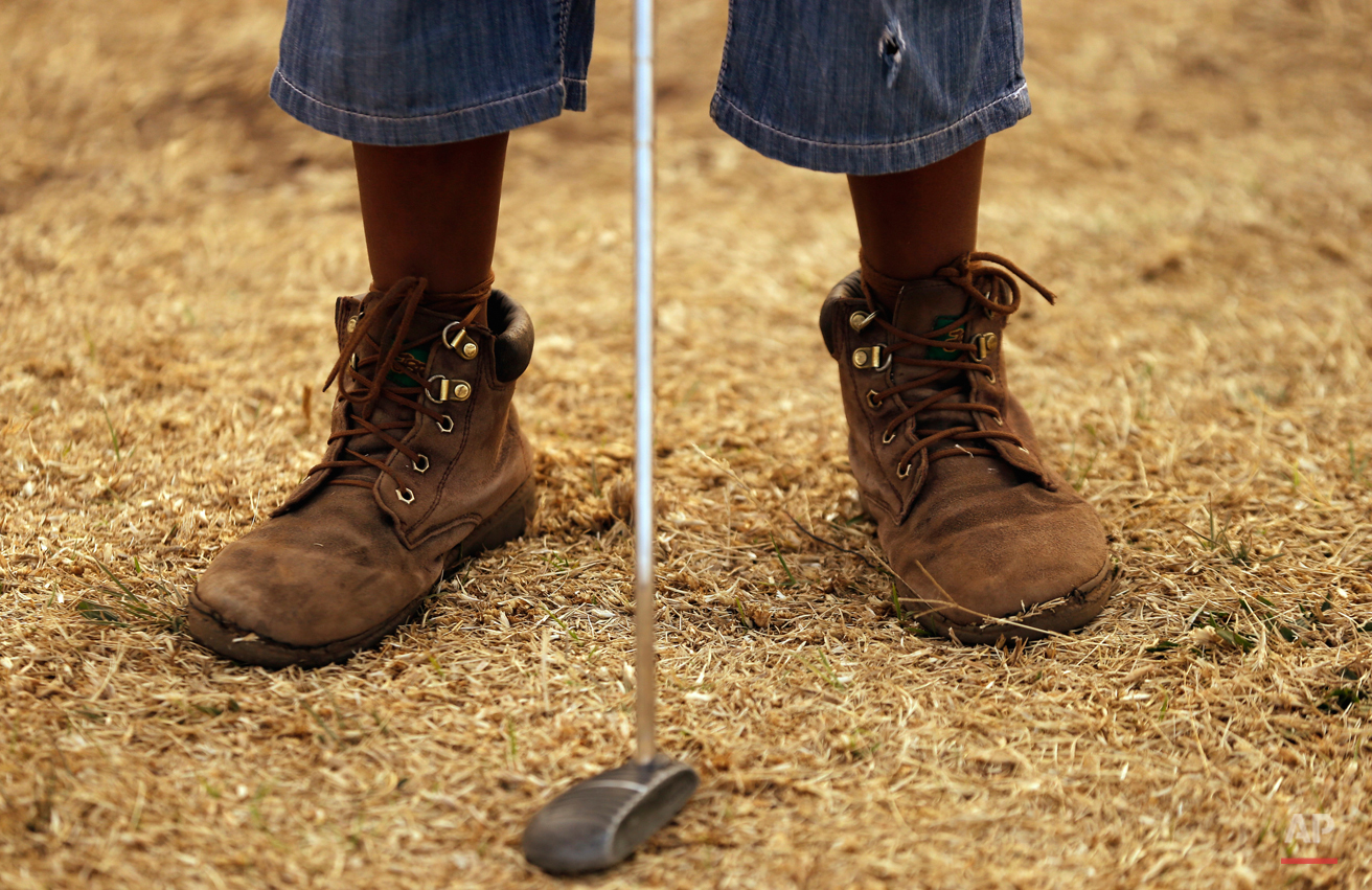  In this Thursday, July 16, 2015 photo ten-year-old Amohela Mokoena, plays a putt during a golf game at a park in Katlehong township, east of Johannesburg, South Africa. At first the township children only watched as their retired neighbour and forme