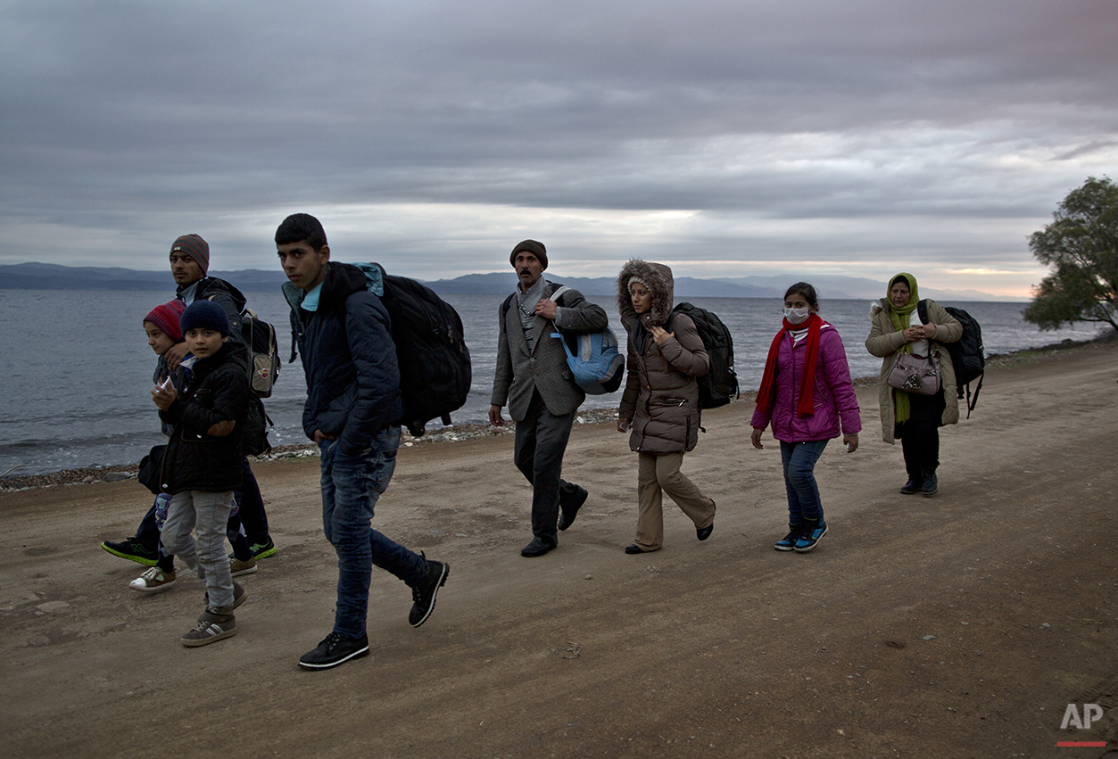  In this Thursday, Dec. 3, 2015 photo, Yazidi refugee Samir Qasu, 45, from Sinjar, Iraq, and his wife Bessi, 42, their two daughters Delphine, 18, Dunia 13, and their two sons Dilshad, 17, and Dildar, 10, walk toward a gathering point to board a bus 