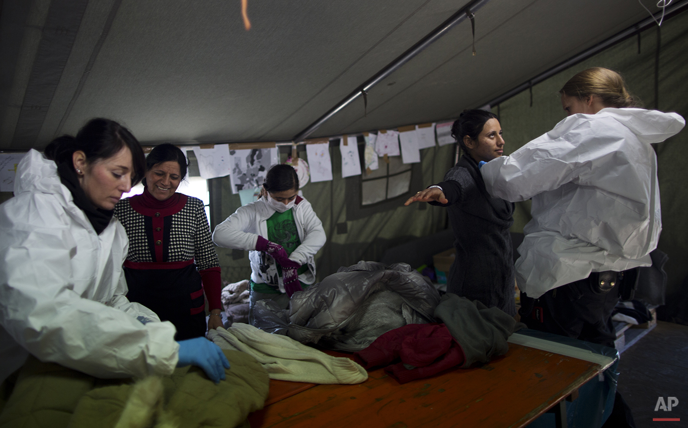  In this Tuesday, Dec. 8, 2015 photo,  Delphine Qasu, 18, a Yazidi refugee from Sinjar, Iraq, right, is body searched by a German police officer next to her sister Dunia, 10, and her mother Bessi, 42, shortly after crossing from Austria to Germany, i