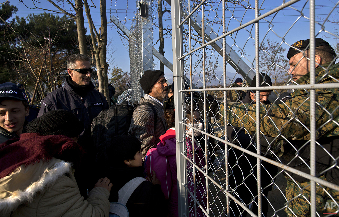  In this Saturday, Dec. 5, 2015 photo, Yazidi refugee Samir Qasu, 45, center, from Sinjar, Iraq, and his family approach Macedonian army officers as they cross a fence at the Greek-Macedonian border, near the northern Greek village of Idomeni. Within