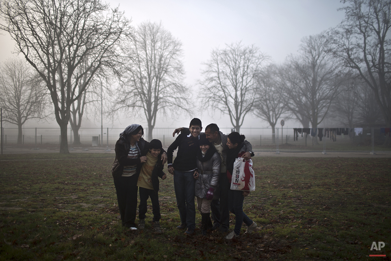  In this Thursday, Dec. 10, 2015 photo, Qasu family, a Yazidi refugee family from Sinjar, Iraq, laugh shortly before posing for a picture outside their new temporary home at Patrick Henry Village, in Heidelberg, Germany. (AP Photo/Muhammed Muheisen) 