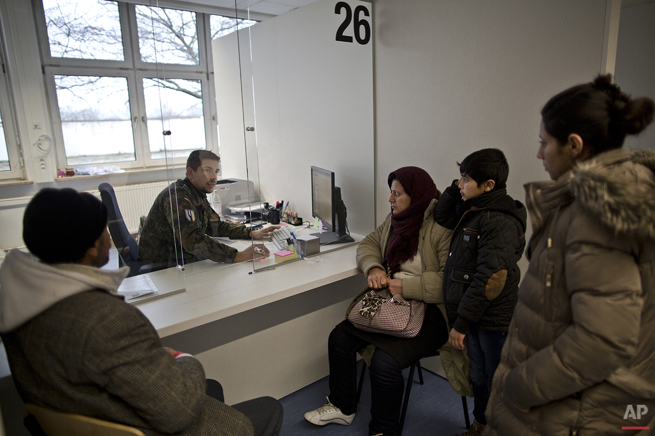  In this Wednesday, Dec. 9, 2015 photo, a German army soldier fills in the details of Qasu family, a Yazidi refugee family from Sinjar, Iraq, as part of their asylum seeking process at the Central Registration Centre in Patrick Henry Village in Heide