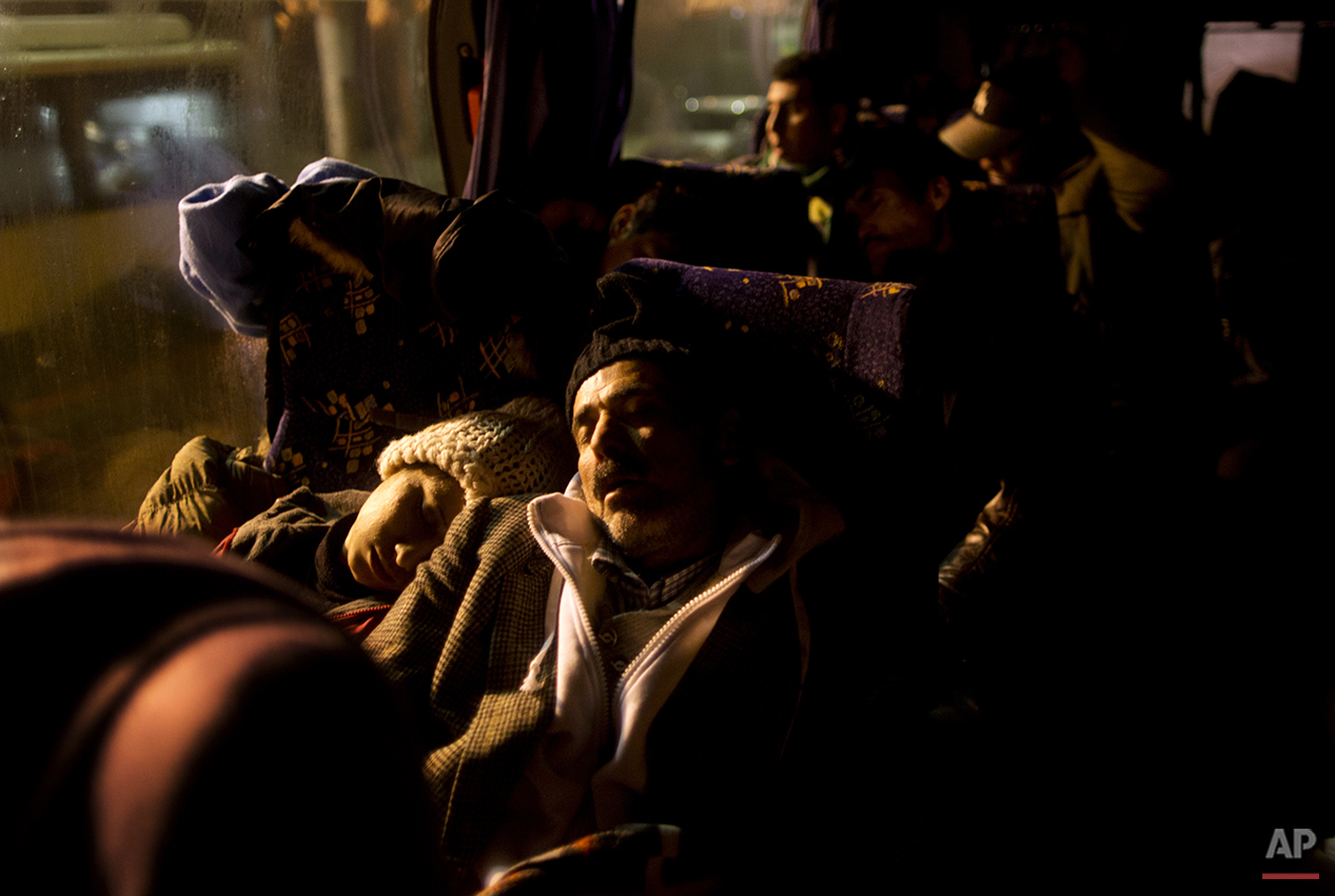  In this Sunday, Dec. 6, 2015 photo, Delphine Qasu, 18, a Yazidi refugee from Sinjar, Iraq, and her father Samir, 45, sleep in a bus while waiting with the rest of their family to be transported to the train station in Sid where Serbian authorities l