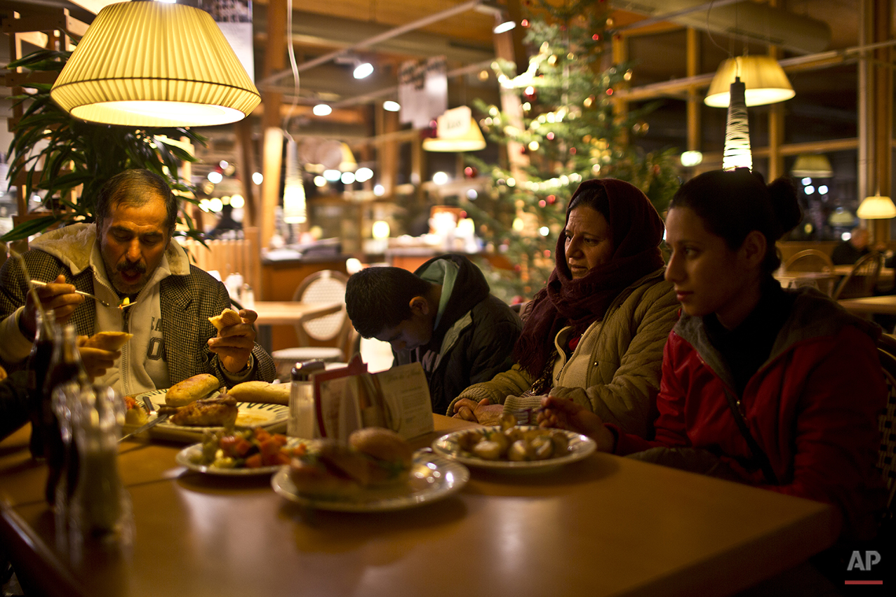  In this Monday, Dec. 7, 2015 photo, Samir Qasu, 45, left, a Yazidi refugee from Sinjar, Iraq, and his son Dilshad, 17, and his wife Bessi, 42, and his daughter Delphine, 18, eat in a restaurant at a gas station during a break while being transported