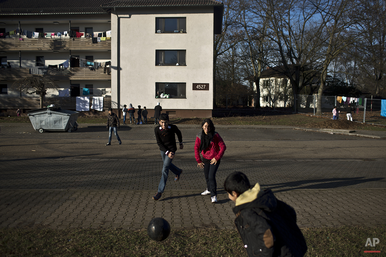  In this Thursday, Dec. 10, 2015 photo, Dilshad Qasu, 17, center, a Yazidi refugee from Sinjar, Iraq, plays football with his sister Delphine, 18, and his brother Dildar, 10, near their new temporary home at Patrick Henry Village, in Heidelberg, Germ