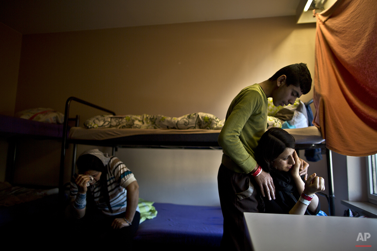  In this Thursday, Dec. 10, 2015 photo, Delphine Qasu, 18, right, a Yazidi refugee from Sinjar, Iraq, is comforted by her brother Dilshad, 17, while crying after talking about their journey to reach Germany, at their new temporary home at Patrick Hen