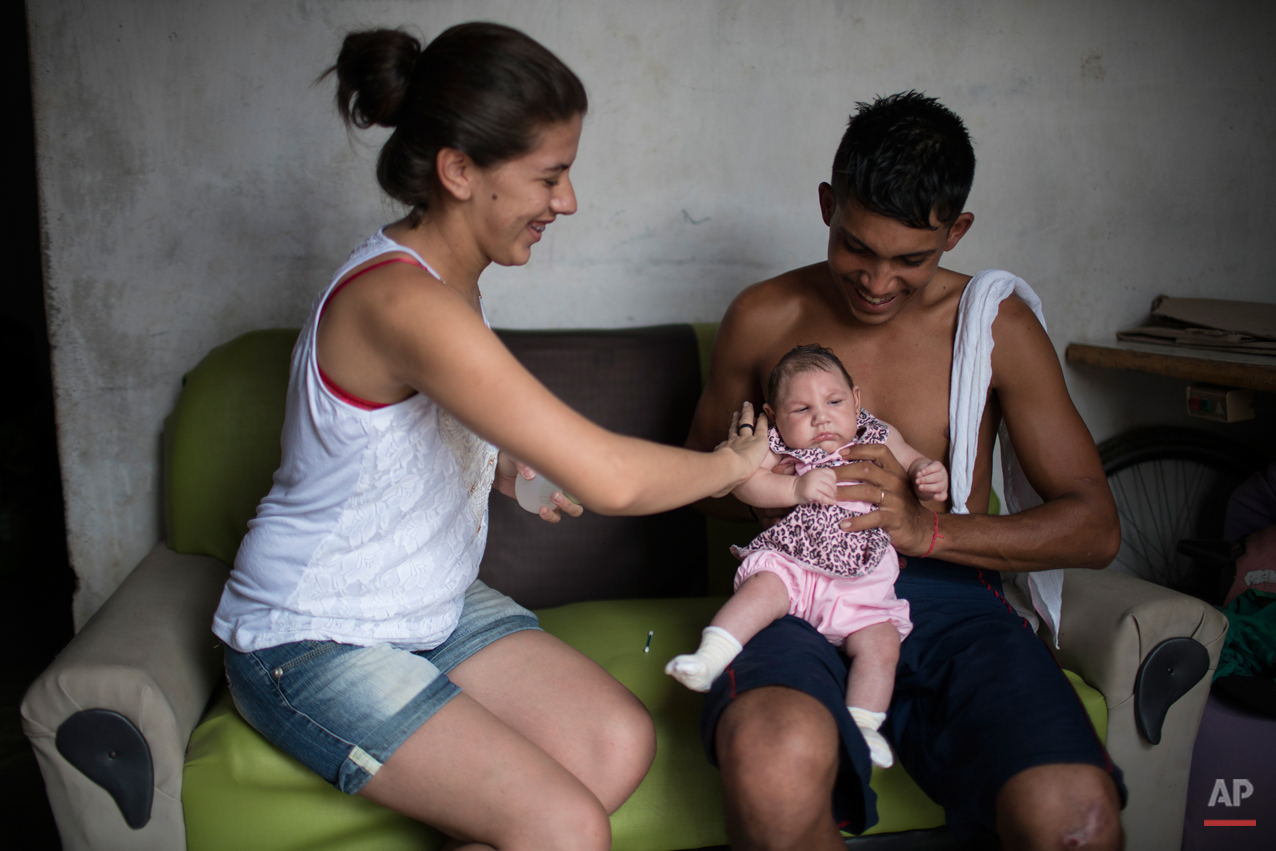  In this Dec. 22, 2015 photo, Angelica Pereira applies perfume on Luiza as her father Dejailson Arruda holds her at their house in Santa Cruz do Capibaribe, Pernambuco state, Brazil. While thereís never before been a detected link between the virus a