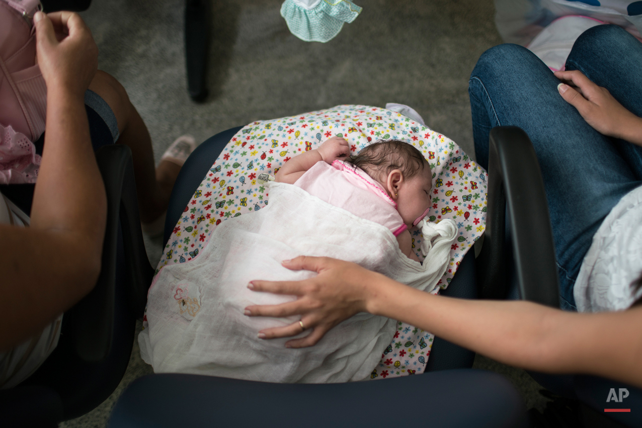  In this Dec. 22, 2015 photo, Angelica Pereira, right, holds her daughter Luiza as she waits for their appointment with a neurologist at the Mestre Vitalino Hospital in Caruaru, Pernambuco state, Brazil.  In November, Brazilian researchers detected t
