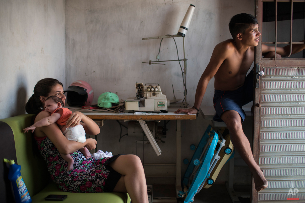  In this Dec. 23, 2015 photo, Angelica Pereira, left, holds her daughter Luiza as she sits with her husband Dejailson Arruda at their home in Santa Cruz do Capibaribe, Pernambuco state, Brazil. Luiza was born in October with a rare condition, known a