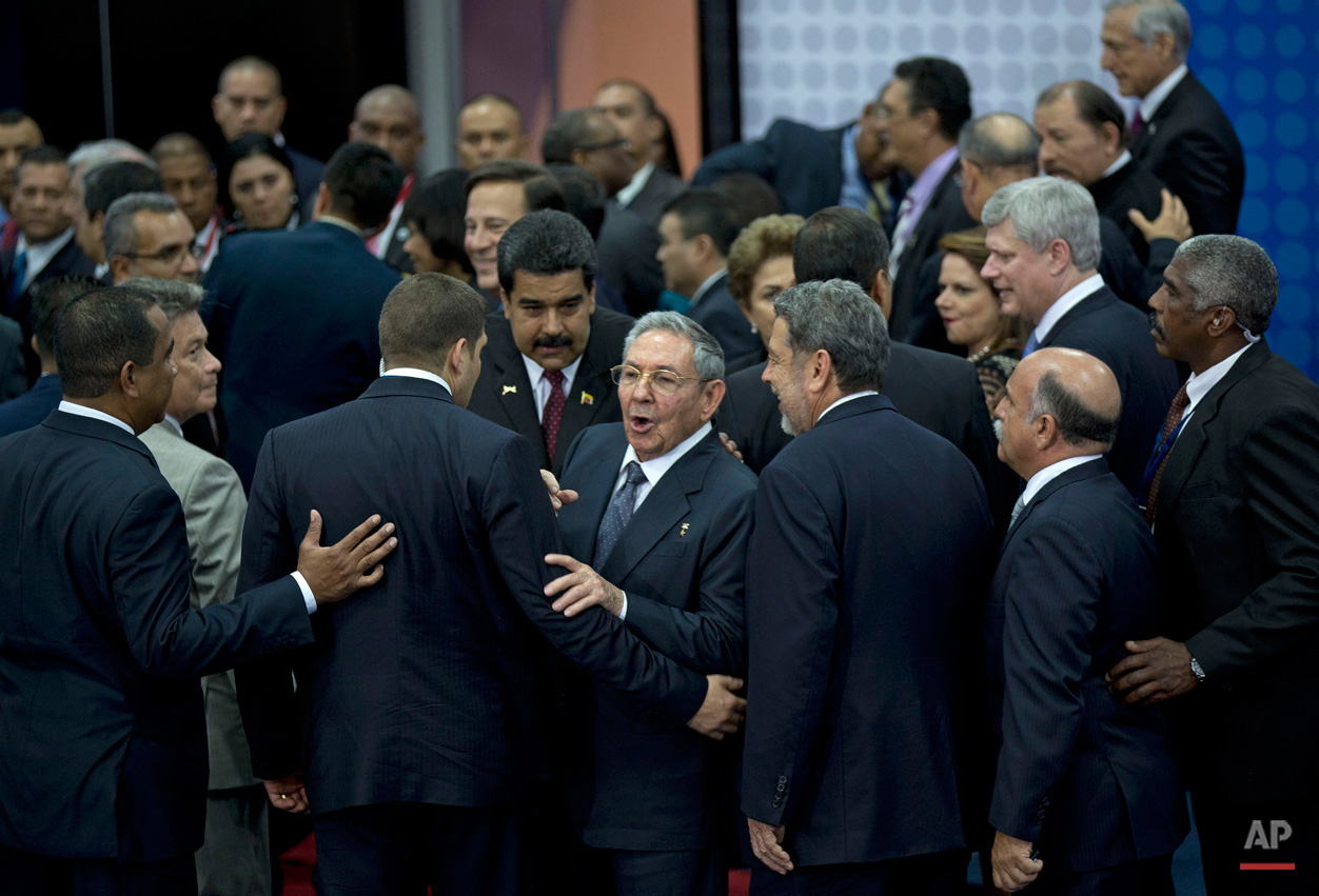 In this April 11, 2015, photo, Cuba's President Raul Castro talks at reporters before turning to leave the staging area of the official group photo of the VII Summit of the Americas in Panama City, Panama. Castro is flanked by his personal assistant and grandson, Raul Guillermo Rodriguez Castro, Venezuela's President Nicolas Maduro, and Prime Minister of Saint Vincent and the Grenadines Ralph Gonsalves. Castro and U.S. President Barack Obama held their first formal meeting in more than half a century on Saturday, clearing the way for a normalization of relations. (AP Photo/Ramon Espinosa)
