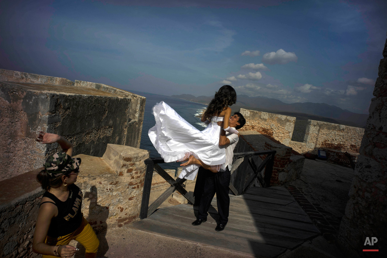 In this July 27, 2015, photo, newlyweds pose for photos during their photo session at the fortress of the Morro in Santiago. While Cuban cities are seeing stagnant visitor numbers, cruise ships provide a promising new potential source of visitors, although dockings remain relatively rare. (AP Photo/Ramon Espinosa)