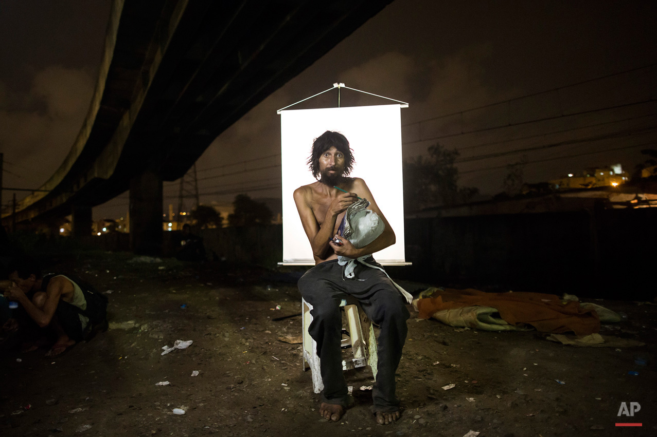 In this March 17, 2015, photo, Renato Dias, 39, writes in his notebook as he poses for a portrait in an open-air crack cocaine market, known as a "cracolandia" or crackland, where users can buy crack, and smoke it in plain sight, day or night, in Rio de Janeiro, Brazil. Dias, who has been using crack for about 4 years, says he uses his notebook as a form of distraction. He writes about super heroes and dreams of becoming one. (AP Photo/Felipe Dana)
