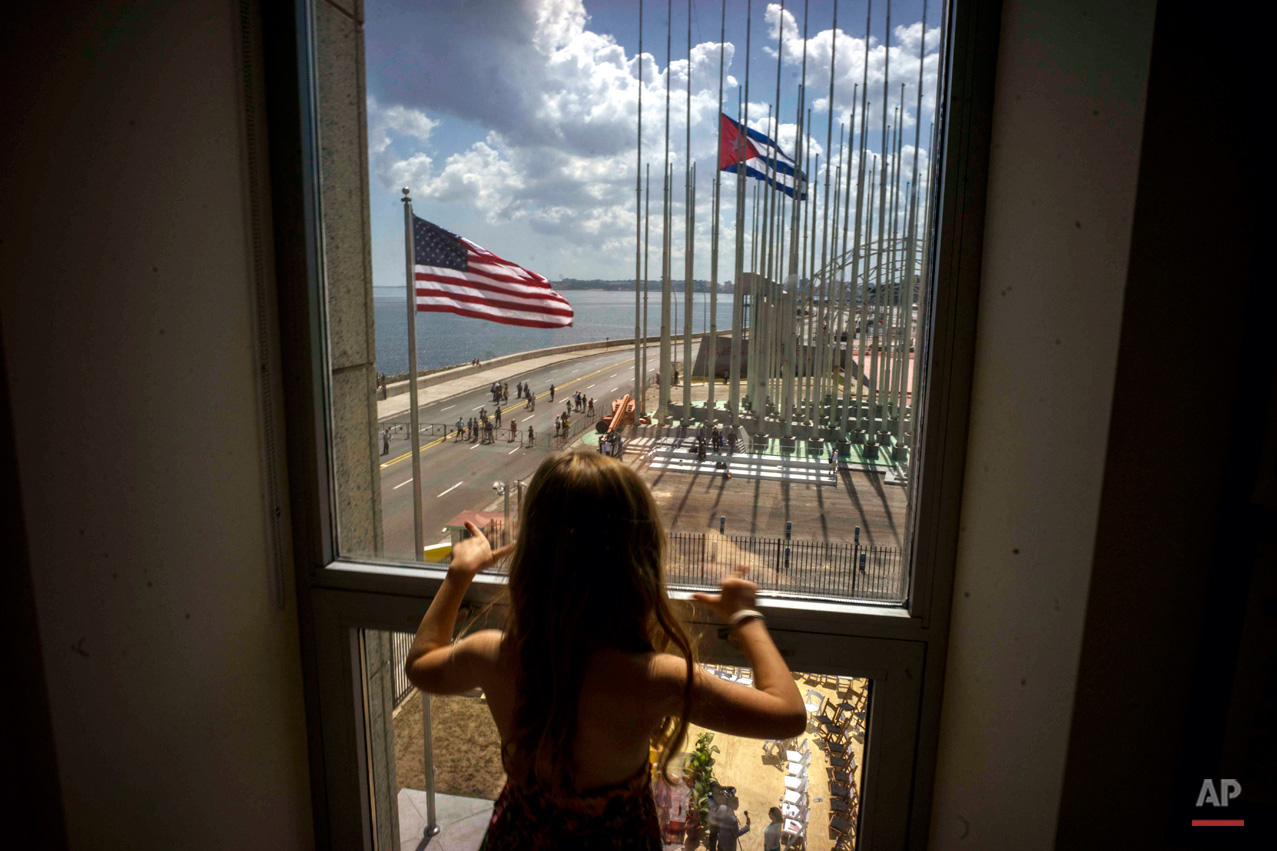 In this Aug. 14, 2015, photo, a girl looks out from the newly opened U.S. Embassy, overlooking the staging area, at the end of the flag raising ceremony in Havana, Cuba. Cuba and U.S. officially restored diplomatic relations July 20. (AP Photo/Ramon Espinosa)