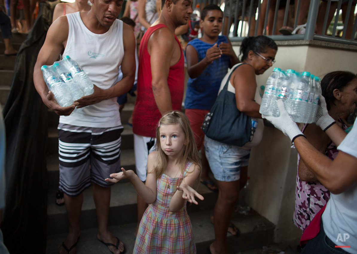 In this Nov. 21, 2015, photo, a girl questions why the man standing next to her was allowed to step ahead of her in a line for free water, at a distribution site, in Colatina, Brazil. Residents were queuing day and night for the bottles of water. (AP Photo/Leo Correa)