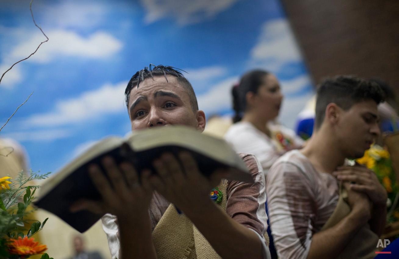 In this Sept. 7, 2015, photo, a young devotee performs while holding a Bible during a service at the Contemporary Christian Church in Rio de Janeiro, Brazil. At the Contemporary Christian Church, which celebrated its ninth anniversary and the opening of its ninth branch with a raucous, theatrical service, homosexuality is celebrated rather than stigmatized. (AP Photo/Silvia Izquierdo)