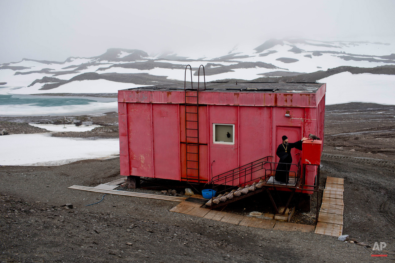 In this Feb. 1, 2015, photo, Russian Orthodox priest Sophrony Kirilov, 38, pets a Skua outside his home in King George Island, Antarctica. Penguins are his favorite animals, but Kirilov says he has also made friends with three large brown Skuas, Antarctic scavenging birds often seen hovering outside his doorstep in search of fresh fish caught by the priest. (AP Photo/Natacha Pisarenko)