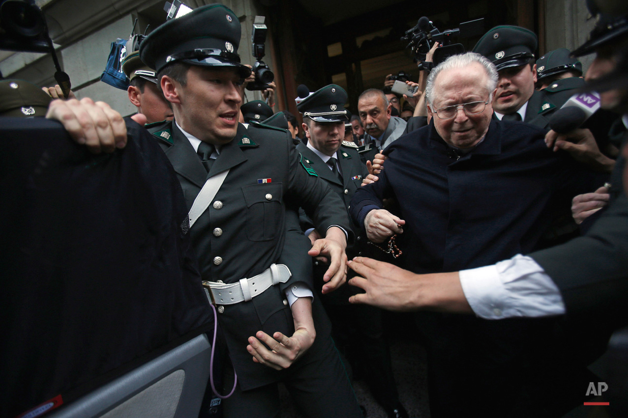 In this Nov. 11, 2015, photo, Fernando Karadima is escorted from a court, after testifying in a case that three of his victims brought against the country's Catholic Church in Santiago, Chile. The Vatican ordered Karadima to life of penance and prayer in 2011 for abusing three young boys. A local judge determined the abuse allegations were truthful but absolved Karadima because the time limit had expired for prosecution. The three victims who filed the suit accuse the Chilean Catholic church of a cover up. The church has rejected the accusation. (AP Photo/Luis Hidalgo)