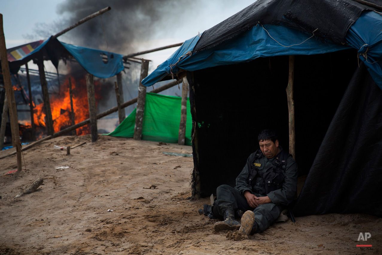 In this Aug. 12, 2015, photo, a police officer rests during the destruction of an illegal gold mining camp in the area known as La Pampa, in Peru's Madre de Dios region. Authorities have launched 15 such operations here in Madre de Dios state since declaring unpermitted, wildcat mining a crime in 2012, blasting dredges, backhoes and motors to bits and expelling thousands of miners and their families from muddy makeshift jungle settlements. (AP Photo/Rodrigo Abd)