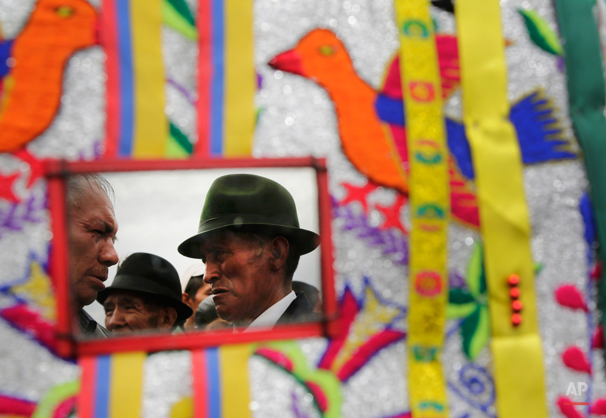 In this June 7, 2015, photo, men are reflected in†a mirror†on a†costume during the Corpus Christi dance in Pujili, Ecuador. Pujili dancers, their costumes representing the Andean condor, perform†on the streets of the town in a mix of Catholic beliefs and indigenous ancestral traditions of the harvest. (AP Photo/Dolores Ochoa)
