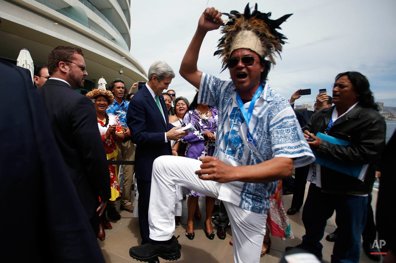 In this Oct. 5, 2015, photo, a man from Easter Island dances as U.S. Secretary of State John Kerry, behind, is given an Easter Island flag on the sidelines of the Our Ocean international conference on marine protection in Vina del Mar, Chile. President Barack Obama declared new marine sanctuaries in Lake Michigan and the tidal waters of Maryland on Monday, while Chile blocked off a vast expanse of the Pacific Ocean near the world-famous Easter Island from commercial fishing and oil and gas exploration. (AP Photo/Luis Hidalgo)