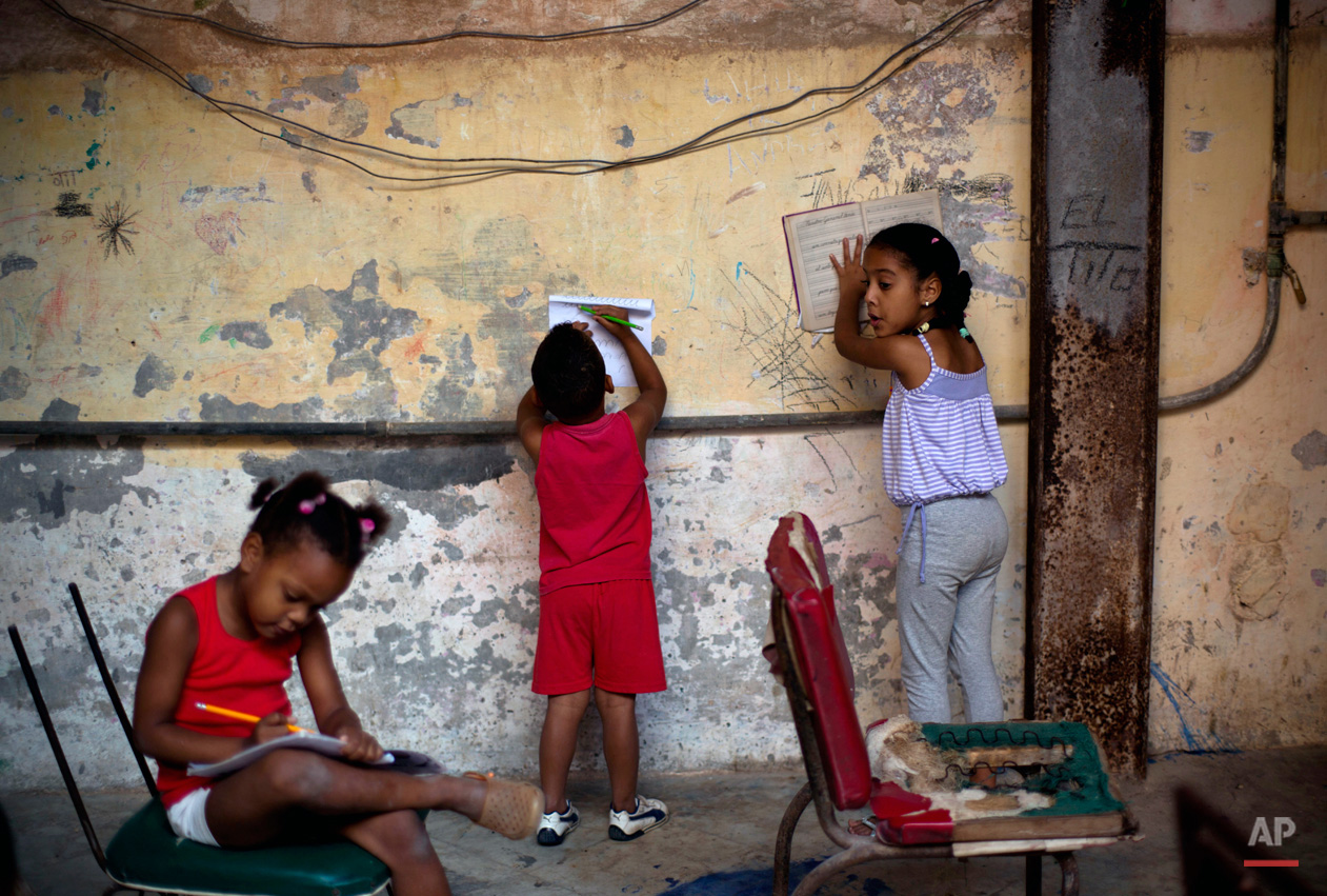 In this Jan. 19, 2015, photo, kids do their homework inside the courtyard of an apartment building in Havana, Cuba, Monday. Cuba has so far offered a guardedly positive reception to President Barack Obama's loosening of the trade embargo on Cuba, saying it welcomes the full package of new economic ties on offer, but it insists it will maintain its one-party political system and centrally planned economy. (AP Photo/Ramon Espinosa)
