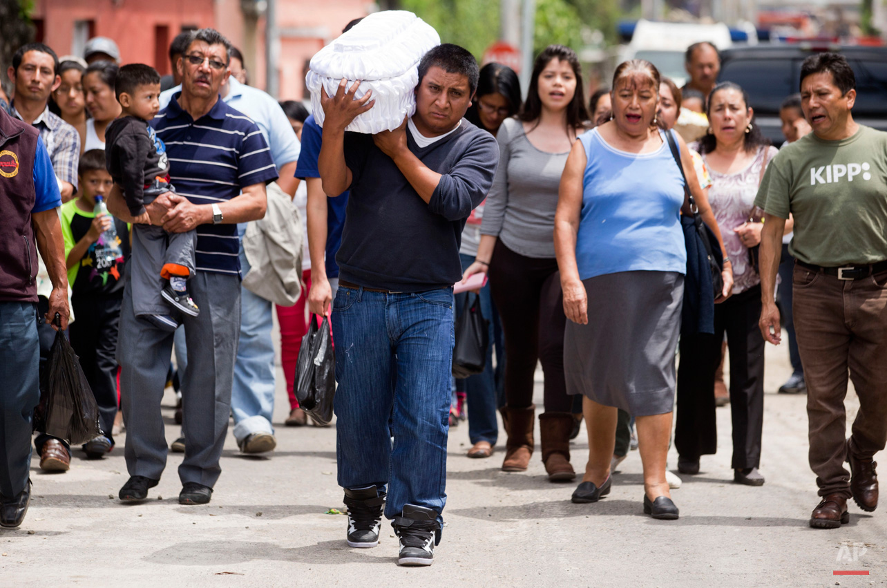 In this Oct. 3, 2015, photo, Welsar Nazario carries the coffin of his five-month-old nephew Alezandro Macario, who died in a mudslide, to the Santa Catarina Pinula cemetery on the outskirts of Guatemala City. Rescue workers recovered more bodies early Saturday after a hillside collapsed on homes on Thursday night, while more are feared still buried in the rubble. (AP Photo/Moises Castillo)